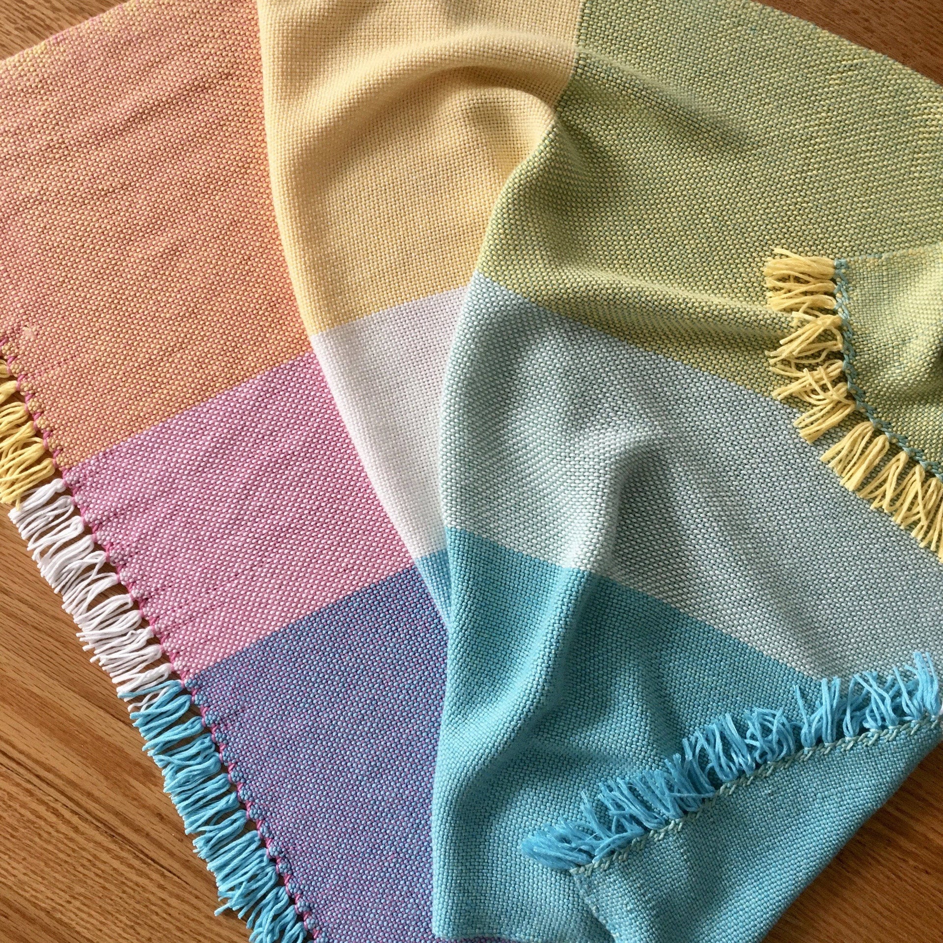 Close up of a hand-woven pastel baby blanket pattern for nursery crib styling.