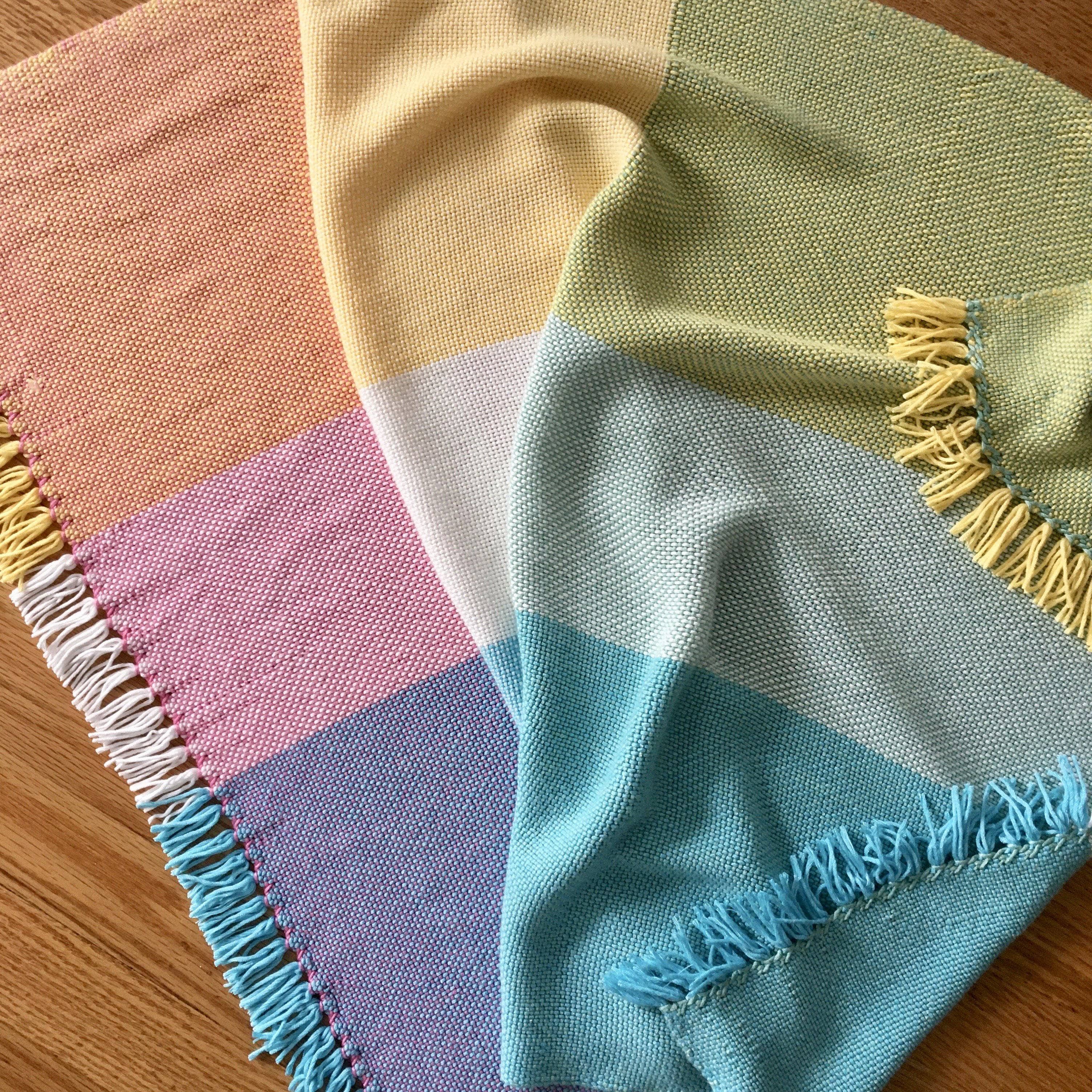 Close up of a hand-woven pastel baby blanket pattern for nursery crib styling.