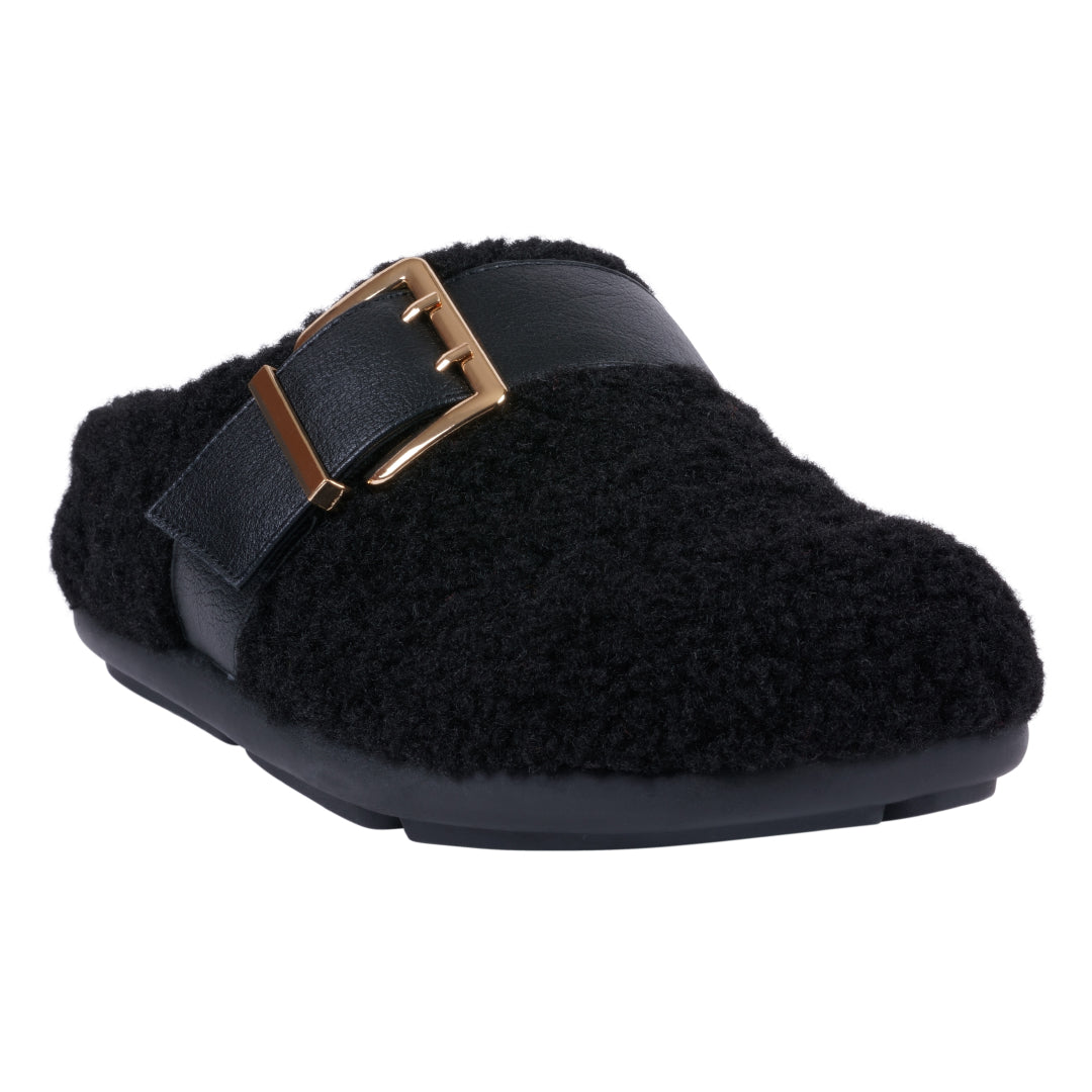 A black slip-on mule slipper featuring a plush, textured upper and a decorative buckle, seen from a side-angle view.