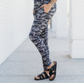 A woman wearing Chris Camo patterned bamboo joggers with a matching top, standing outdoors.
