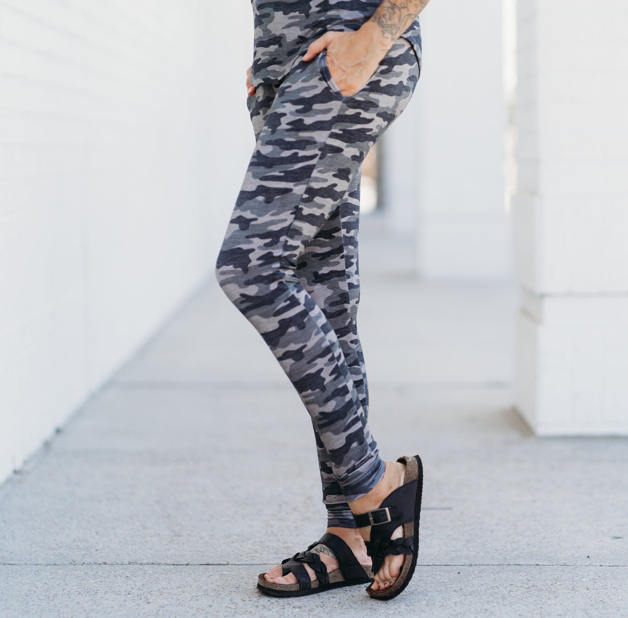 A woman wearing Chris Camo patterned bamboo joggers with a matching top, standing outdoors.