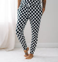 A woman wearing black and white checkered bamboo joggers standing in a bright room.