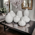 Collection of various white textured ceramic Whitney vases displayed on a table
