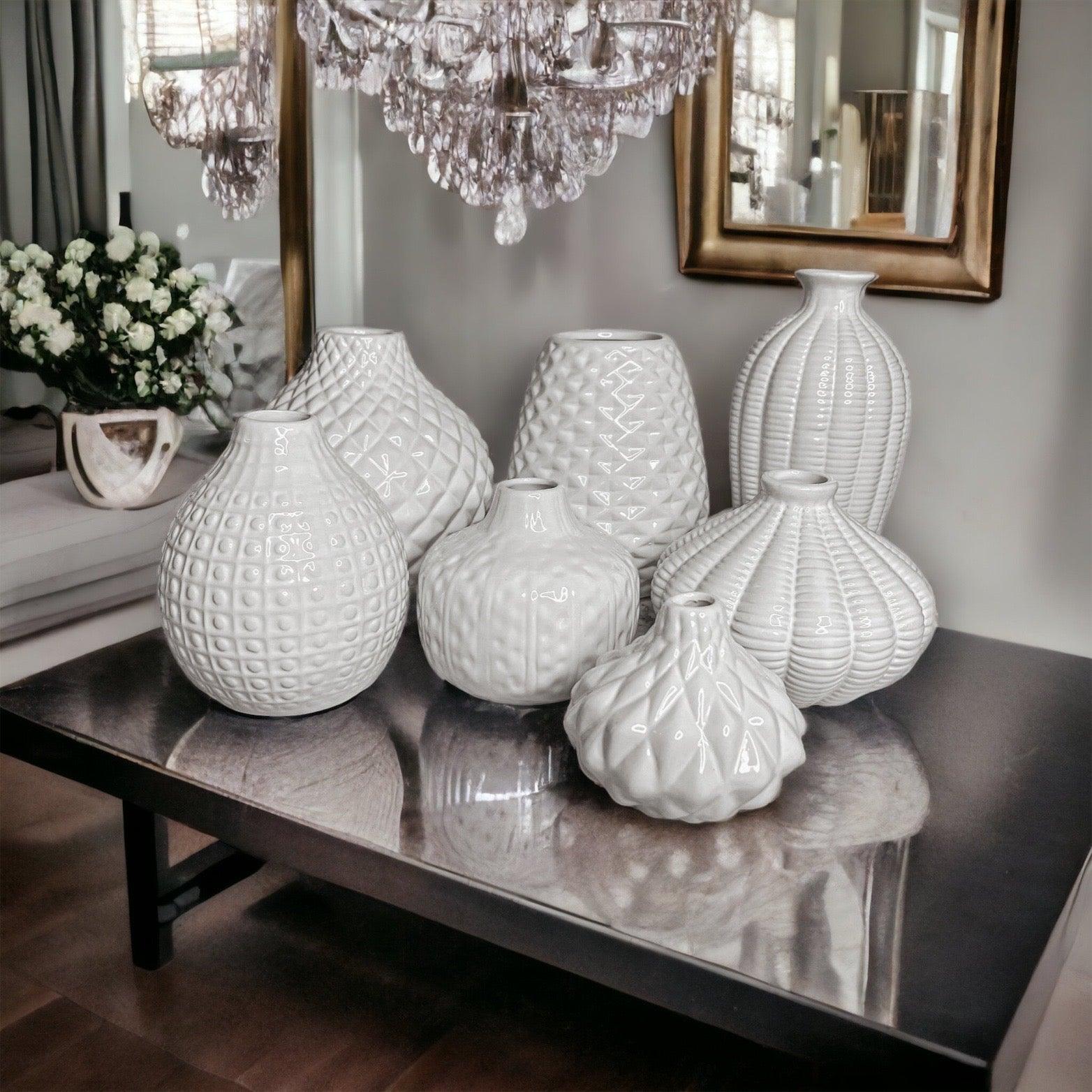 Collection of various white textured ceramic Whitney vases displayed on a table