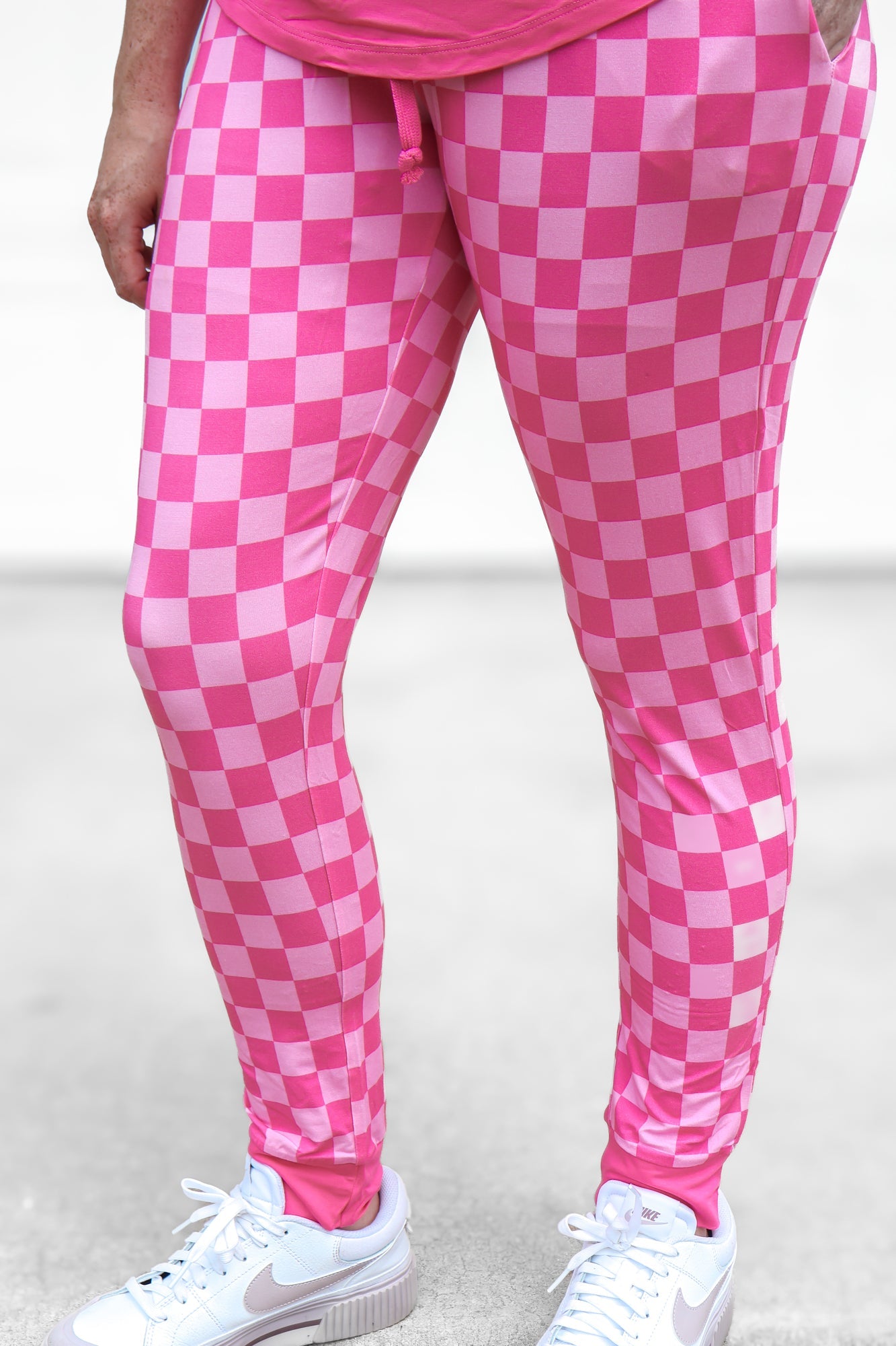 Woman wearing pink checkered bamboo joggers standing in a studio