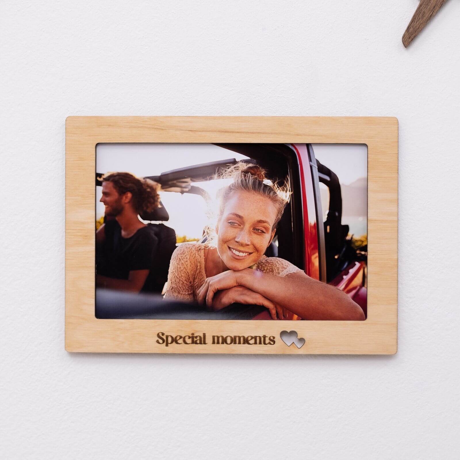 Set of 9 light-wood photo frames arranged on a wall in a minimalist, Scandinavian-style living room.