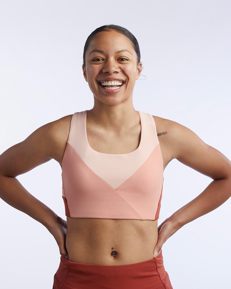 Athlete wearing a Pionxr Bra Top featuring light pink, peach, and dark rust color-blocking.