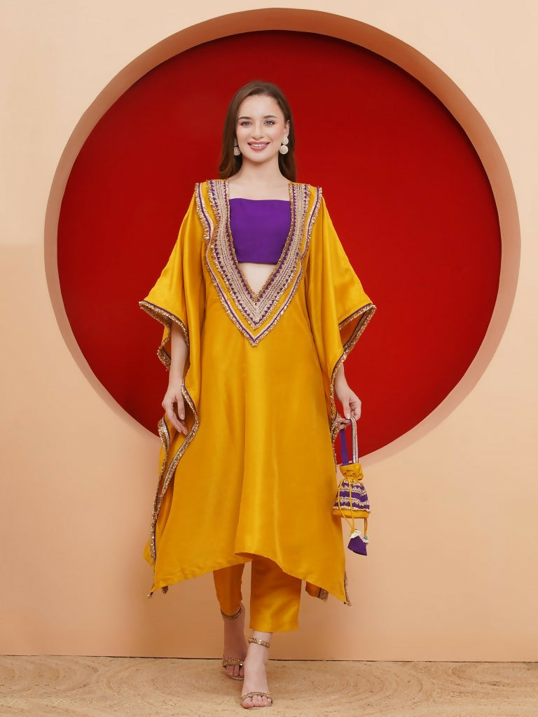 Woman wearing a vibrant mustard yellow silk kaftaan set with lace detailing and a matching potli bag