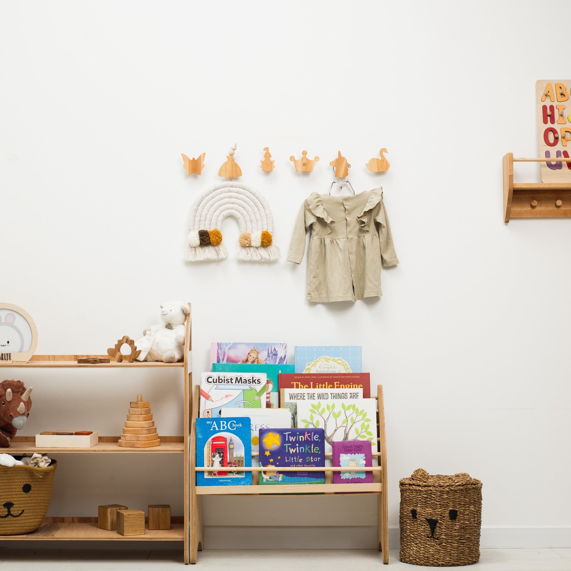 Set of minimalist light-wood Princess wall hooks mounted on a nursery wall with outfits hanging.