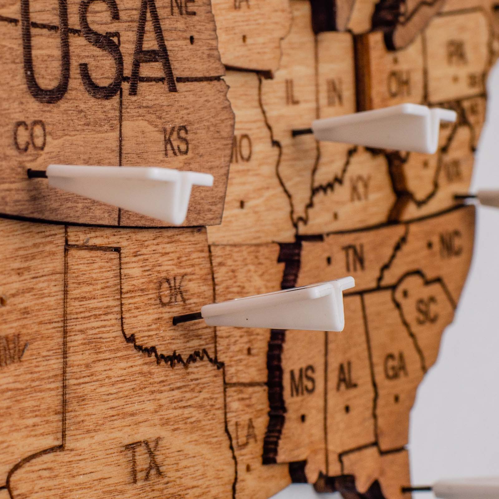 Close up of a white airplane-shaped push pin marking a location on a world map in a modern office.