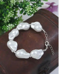 Handmade bohemian style bracelet featuring iridescent white baroque pearls and metallic silver accents
