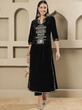 A woman wearing a black velvet kurta set with intricate hand embellishments and three-quarter sleeves.