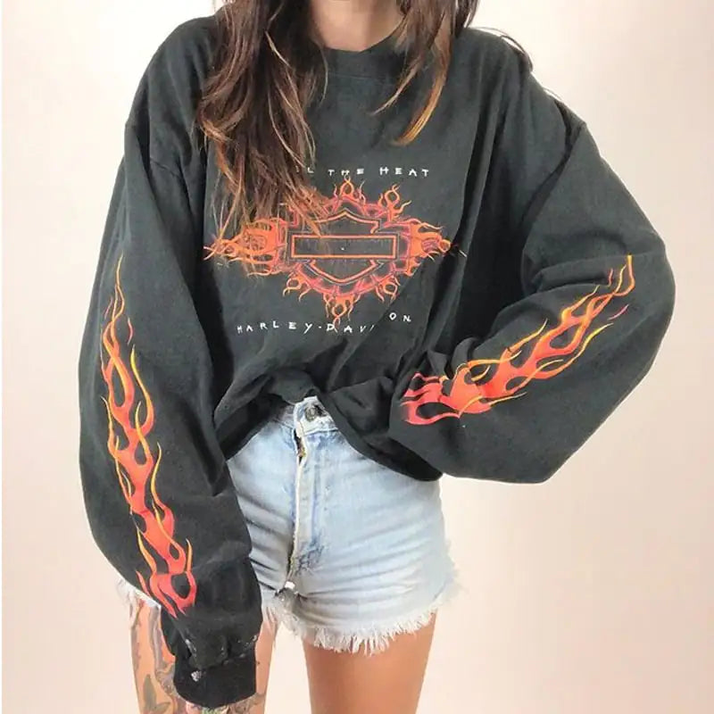 A woman wearing a black long-sleeve sweatshirt with a flaming graphic design on the sleeves and chest.