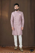 A toddler wearing a pink woven jacquard kurta with white pyjamas for a festive occasion