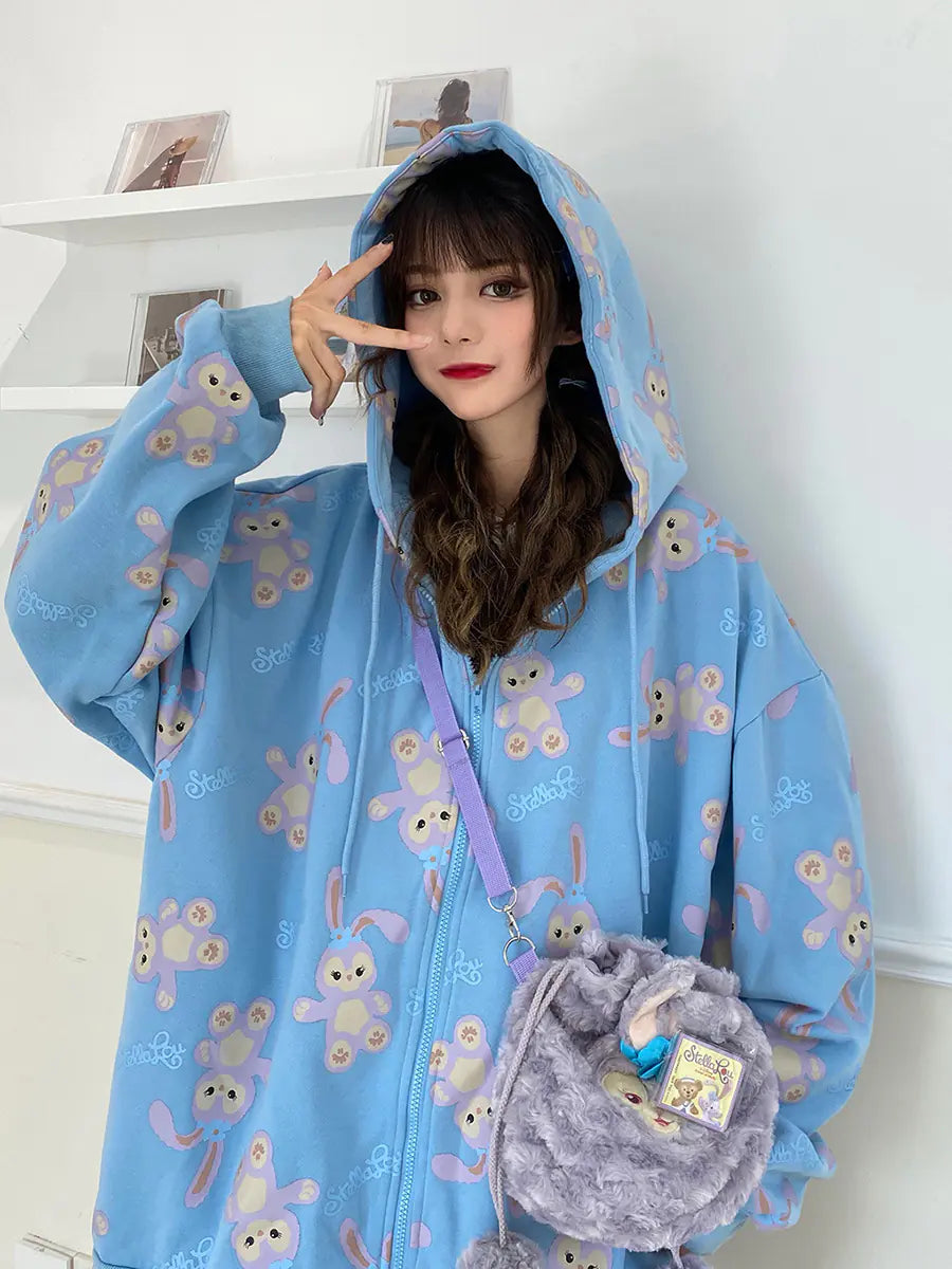 A woman wearing a loose-fit sky blue zip-up hoodie with a cartoon character print.