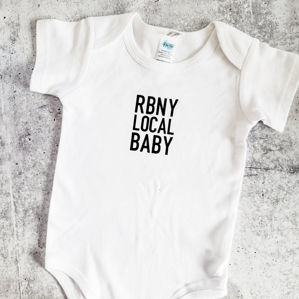 White short sleeve baby bodysuit with RBNY LOCAL BABY text printed in black