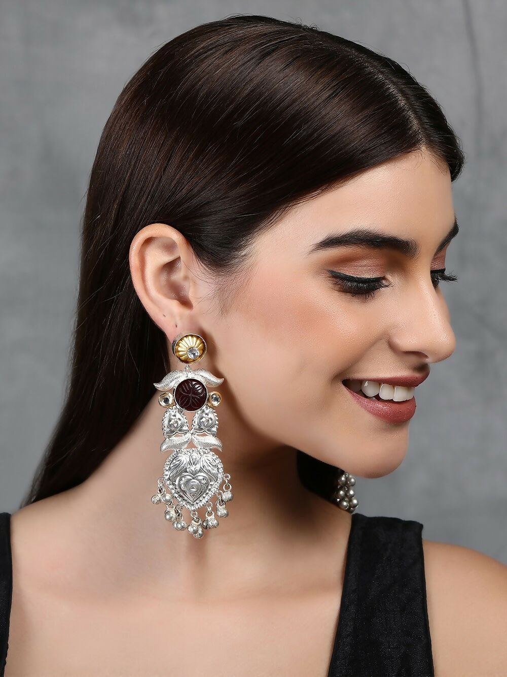 Long silver tone drop earrings featuring intricate patterns and sparkling accent stones.
