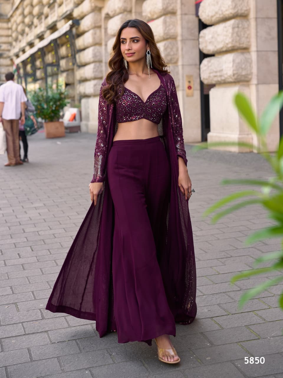 A woman wearing a Purple Heavy Georgette crop top, palazzo pants, and a matching shrug set.