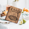 Brown wooden recipe book for pies and tarts with personalized engraving on a kitchen counter.
