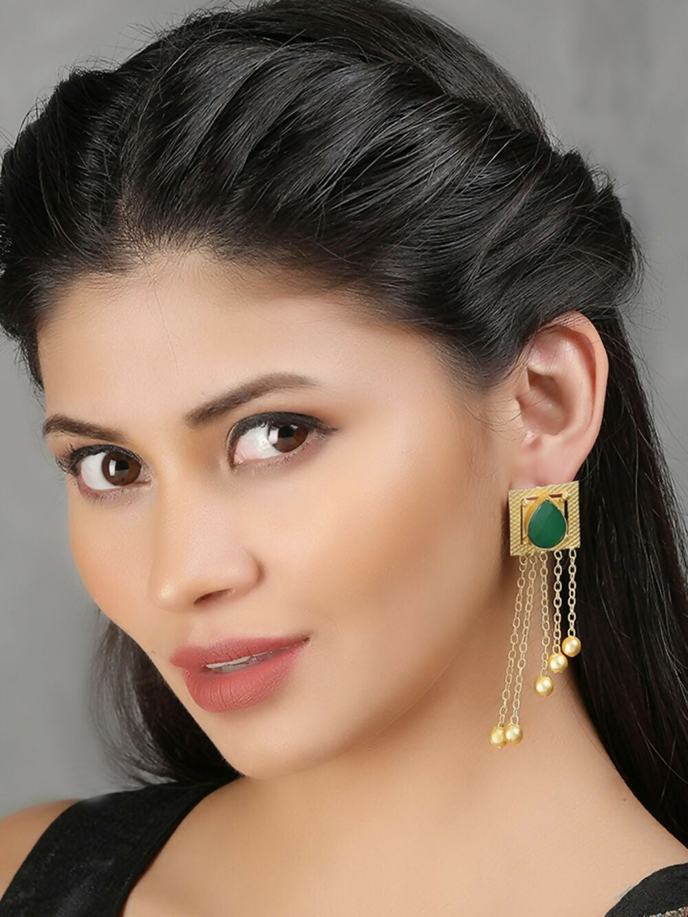 Long matte gold earrings featuring green stones and golden bead detailing.