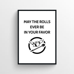 A humorous black and white bathroom sign featuring a winged toilet paper roll and the text May the rolls ever be in your favor.