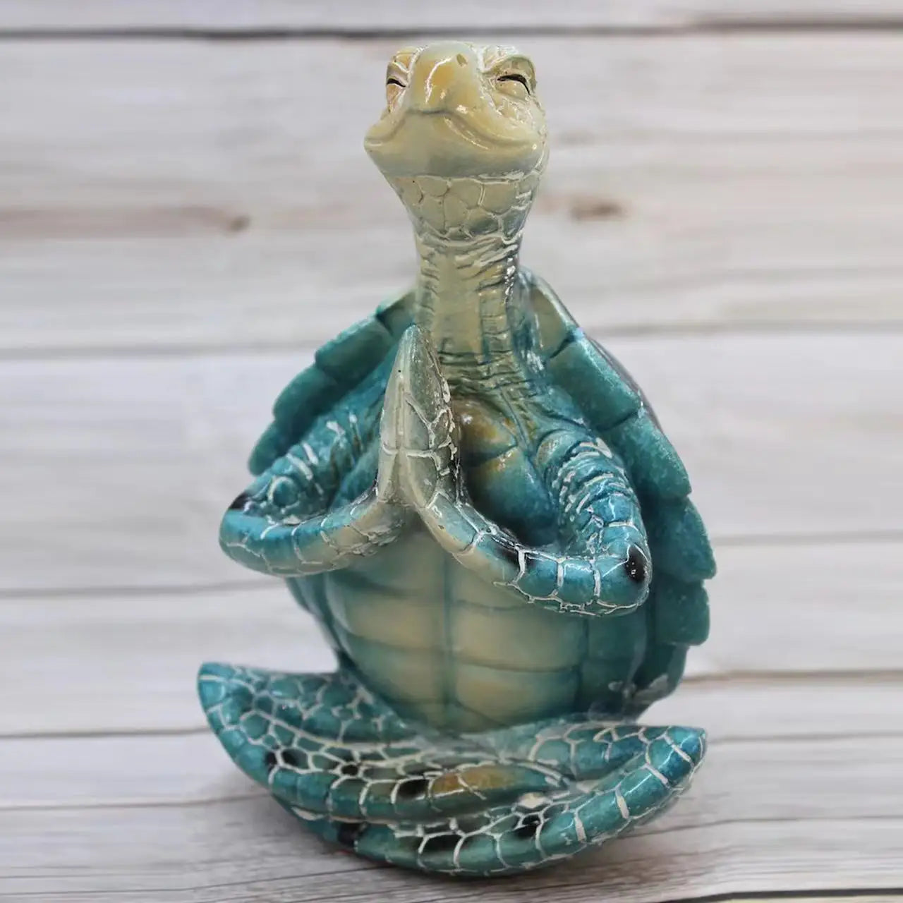 A decorative resin statue of a turtle in a meditative yoga pose with hands together.