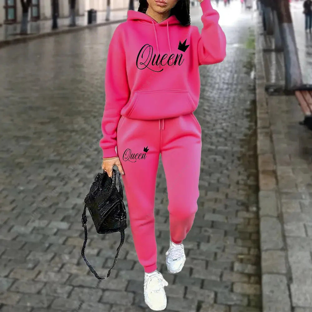 A woman wearing a vibrant pink or maroon 2-piece hoodie and joggers tracksuit with a Queen graphic print.
