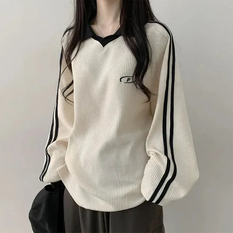 Woman wearing a long sleeve polo pullover sweater with striped sleeve details