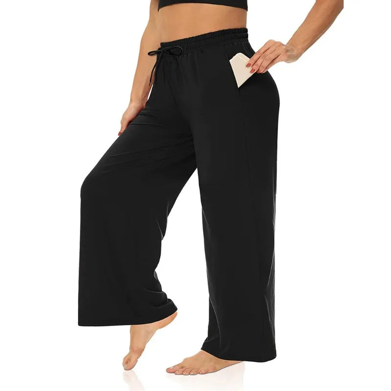 Model wearing black wide-leg lounge trousers with a drawstring waist and side pockets