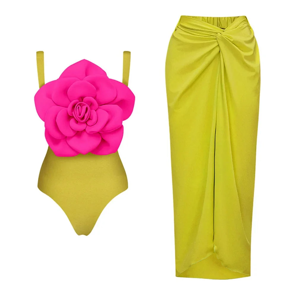 A luxury one-piece swimsuit featuring a large 3D floral accent on the bodice, paired with a matching wrap sarong skirt.