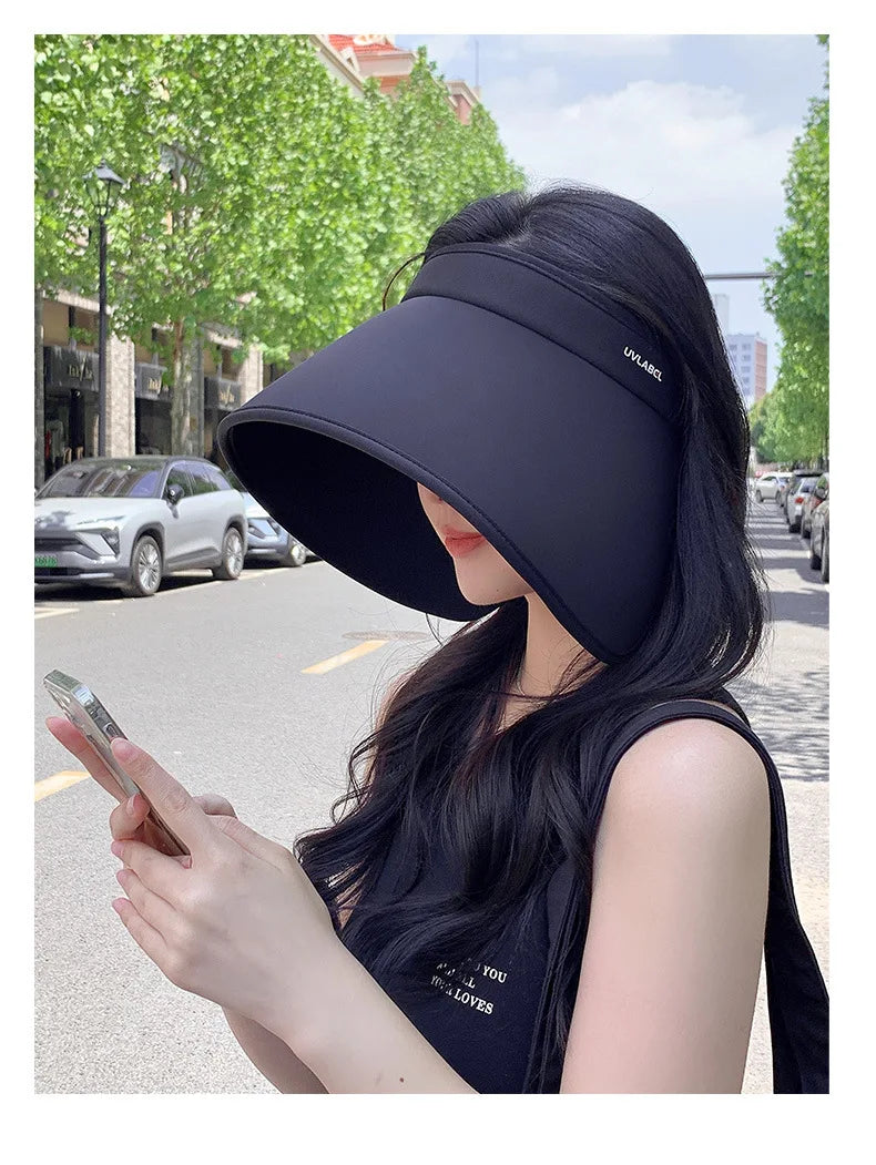 A woman wearing a black wide-brimmed floppy sun visor hat outdoors