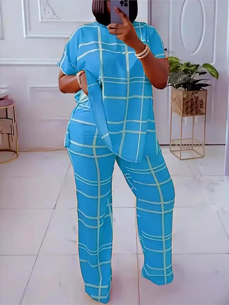 A woman wearing a bright blue two-piece set with a white grid pattern, consisting of a round neck top and matching straight-leg pants.