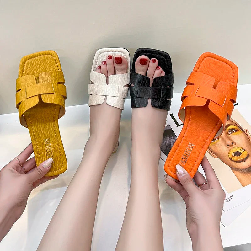 Selection of vibrant flat summer sandals in yellow, white, black, and orange featuring a geometric strap design.