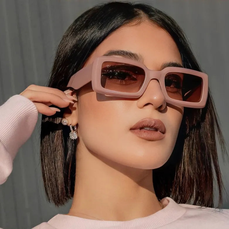Woman wearing stylish beige small rectangle sunglasses outdoors in sunlight