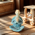 A blue resin meditation turtle statue in a seated prayer pose on a wooden surface