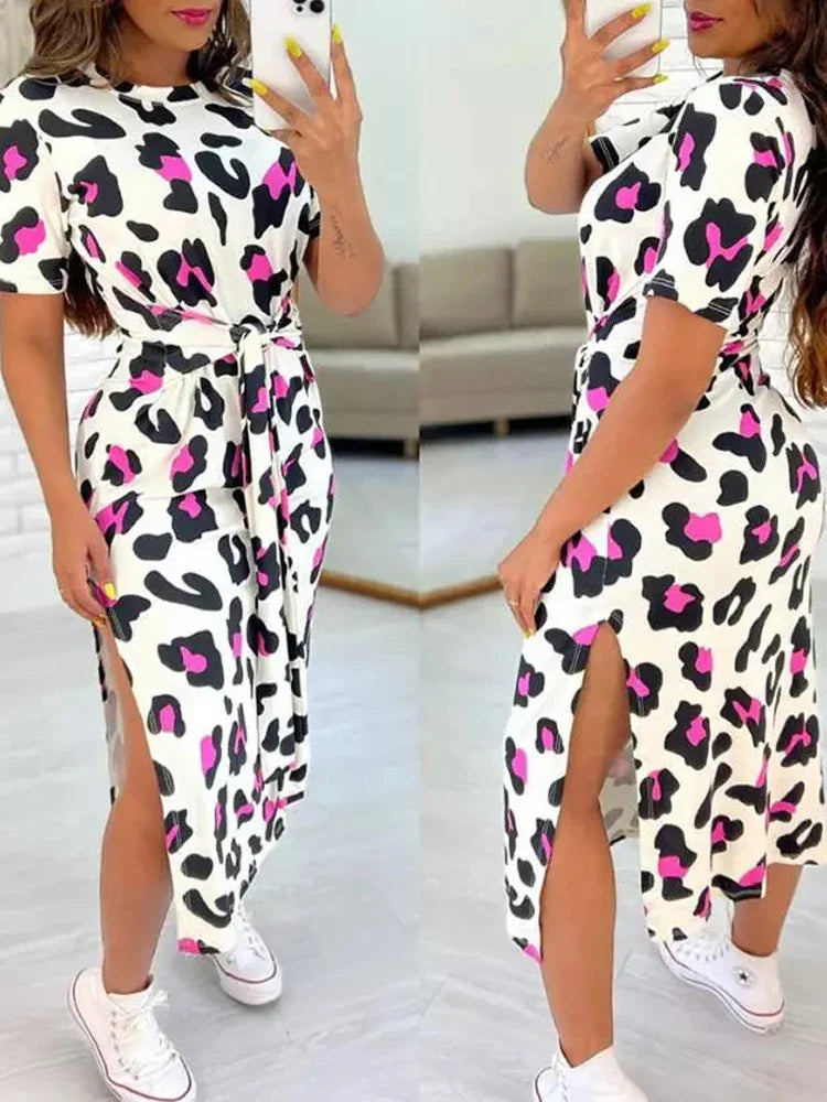 A woman wearing a leopard print midi dress with a tie waist and side slit detail.
