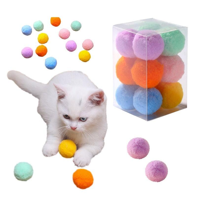 A 12-piece set of colorful plush pom-pom balls for cats in various bright colors including pink, blue, and yellow.