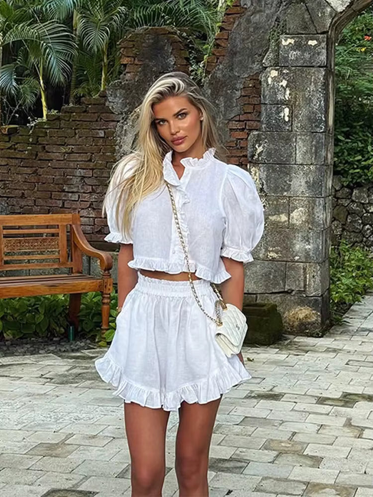 White linen-blend cropped blouse with ruffled high neck and matching shorts.