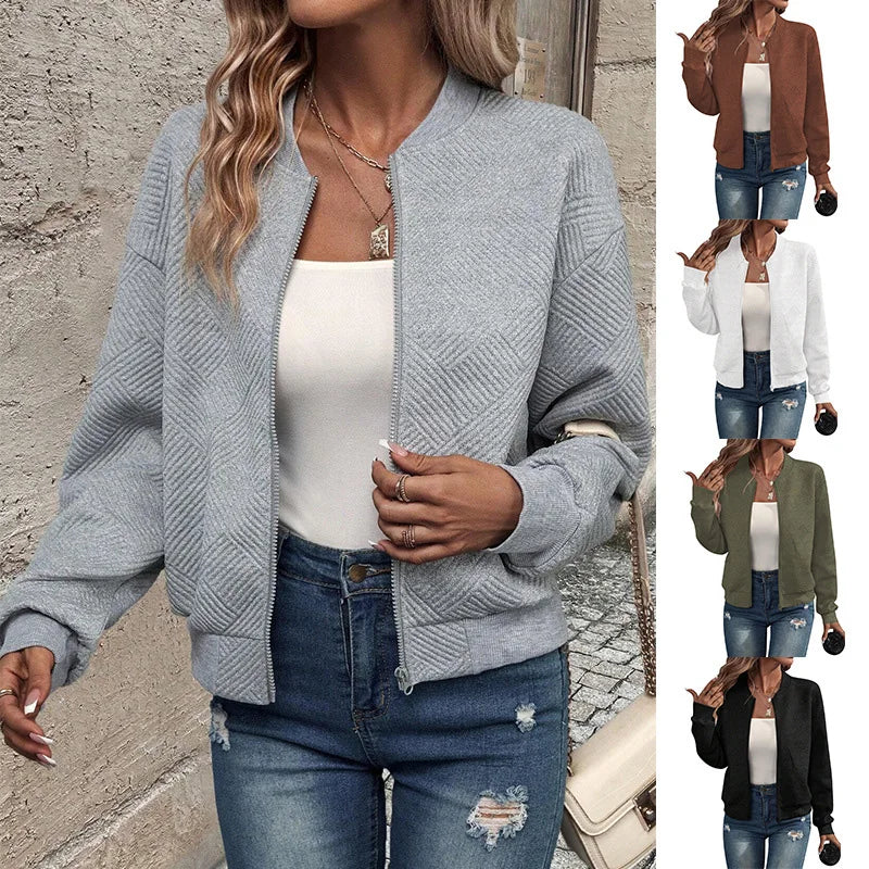 A woman wearing a grey textured zip-up jacket with a stand collar, styled with jeans.