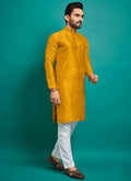 Baby boy wearing a vibrant yellow silk kurta with detailed embroidery and matching pajama