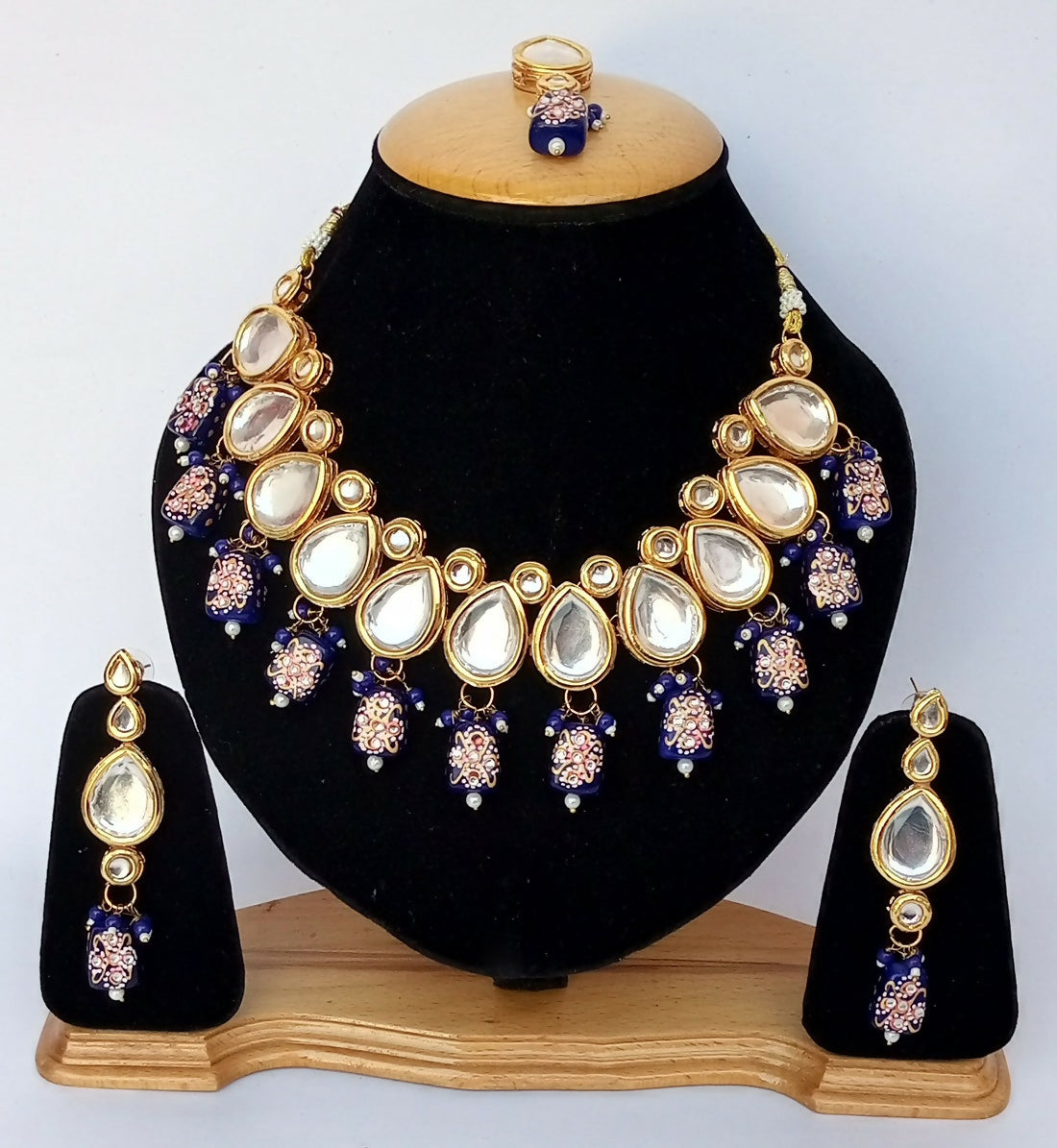 Close up of a blue Kundan stone-studded necklace set with gold plating and adjustable cord.