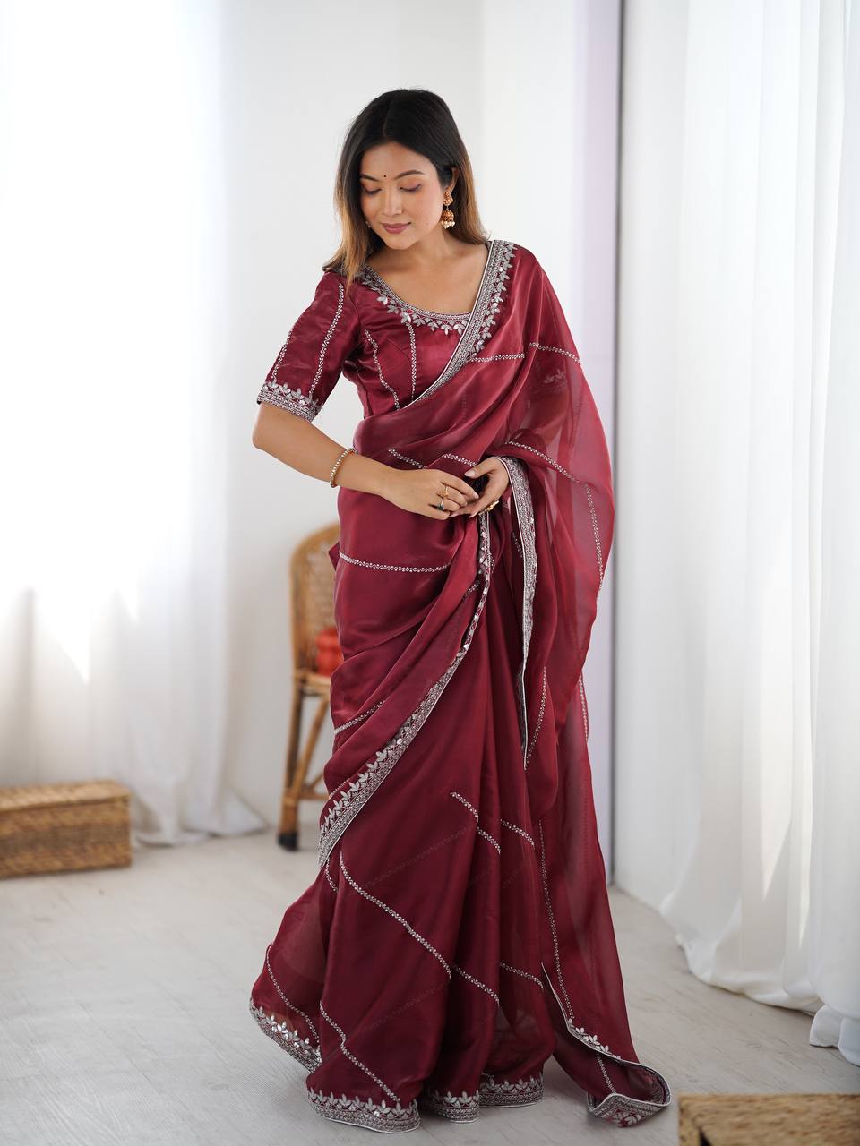 Maroon organza silk party wear saree with intricate thread and sequence embellishments.