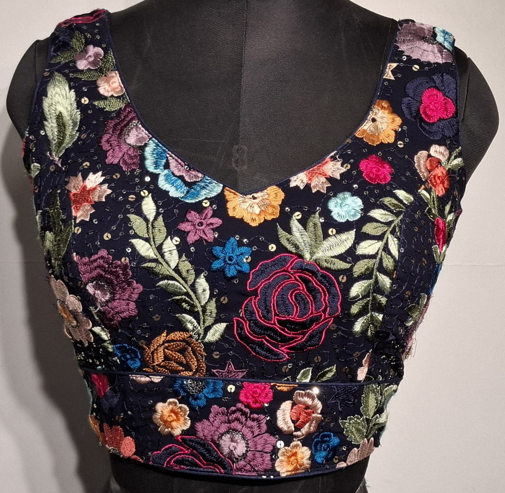 Navy blue readymade blouse with all-over multicolor embroidery and a curved V-neck design.