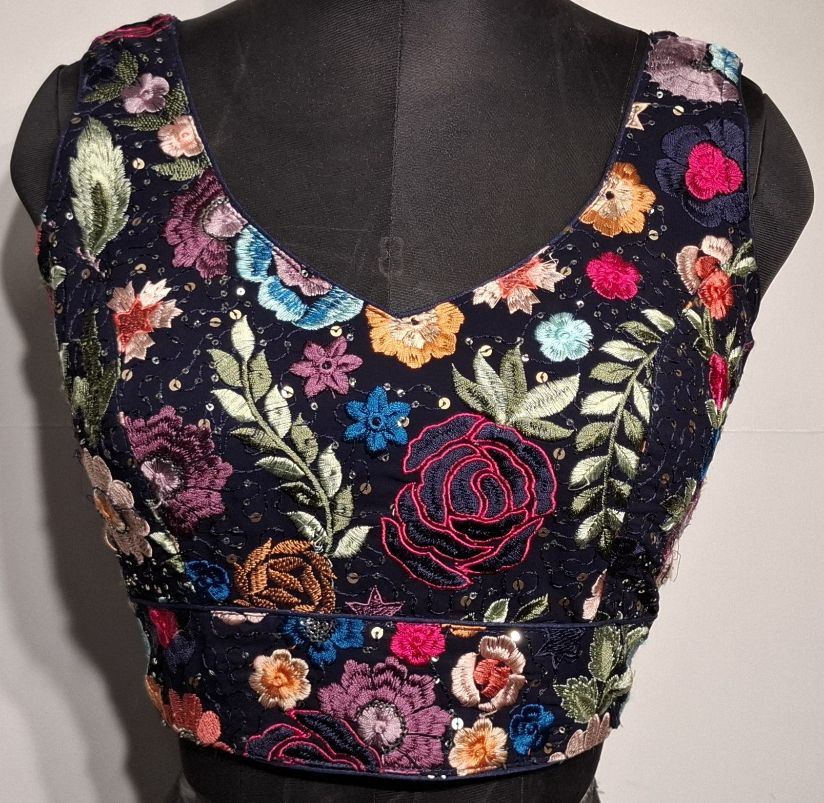Navy blue readymade blouse with all-over multicolor embroidery and a curved V-neck design.