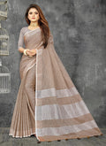 Elegant beige linen saree with a contrast zari border and decorative tassel finish
