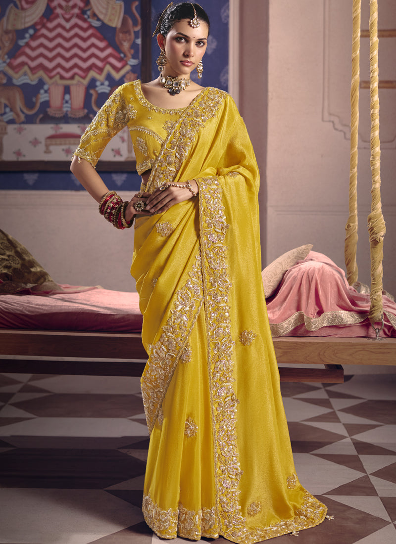 Elegant yellow silk saree with heavy embroidered lace border for wedding guest wear.