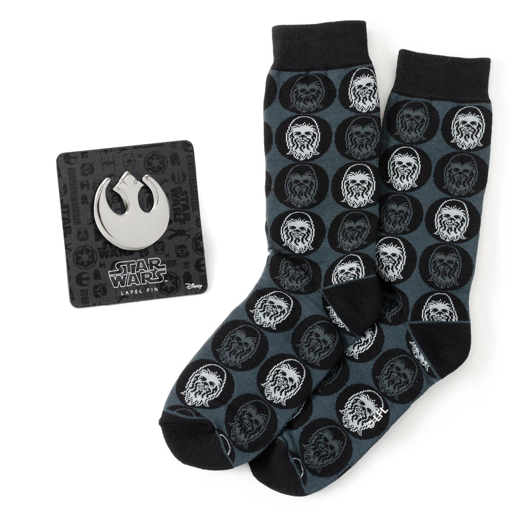 A pair of black crew socks featuring a Chewbacca face pattern alongside a silver Rebel Alliance Starbird crest lapel pin.