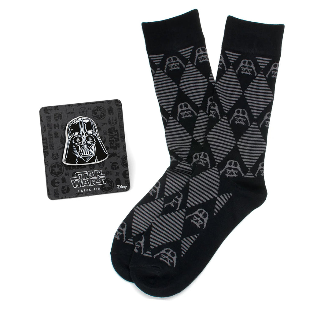 A pair of black and grey argyle socks with Darth Vader helmet patterns, paired with a matching black Darth Vader lapel pin on a display card.