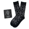 A pair of black and grey argyle socks with Darth Vader helmet patterns, paired with a matching black Darth Vader lapel pin on a display card.