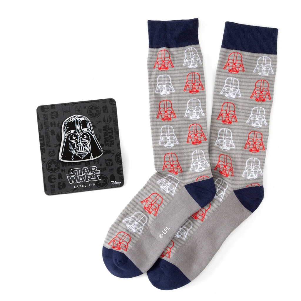 A pair of gray dress socks with a Darth Vader helmet pattern and a matching Darth Vader lapel pin on a display card.